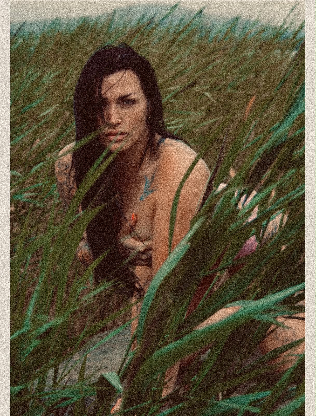 A woman framed by tall green marsh grass at the water's edge